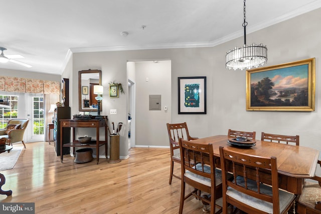 dining area with light wood finished floors, ceiling fan with notable chandelier, baseboards, ornamental molding, and electric panel