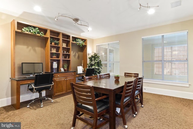 dining room with crown molding, baseboards, rail lighting, and light colored carpet