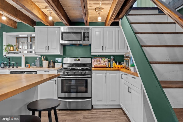 kitchen with white cabinets, appliances with stainless steel finishes, butcher block counters, and light wood finished floors