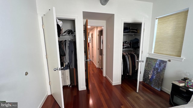 bedroom featuring two closets, baseboards, and wood finished floors