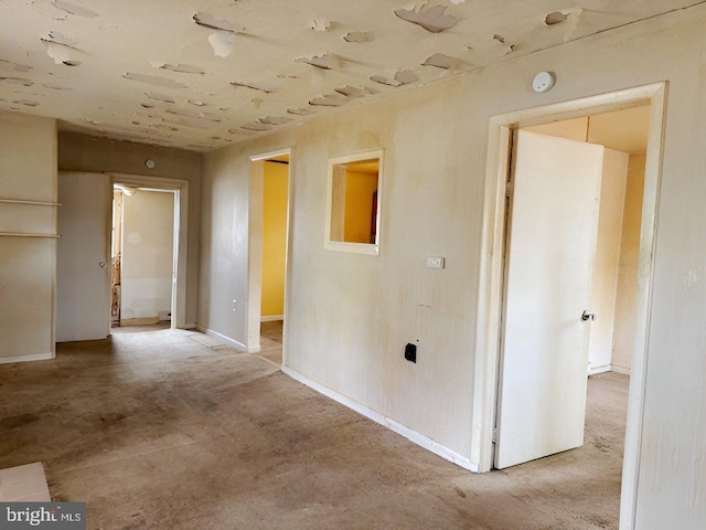 hallway featuring unfinished concrete floors and baseboards