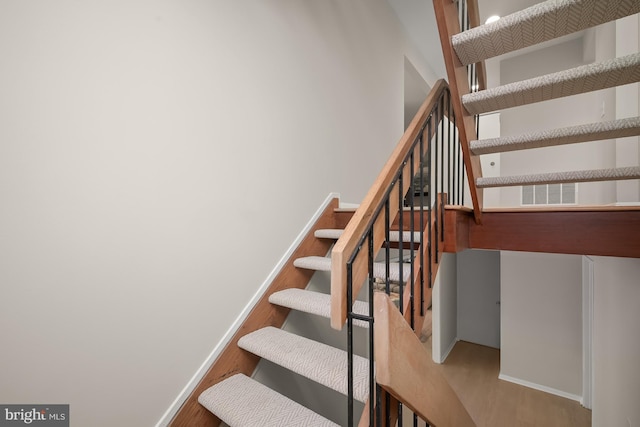 staircase featuring visible vents, wood finished floors, and baseboards
