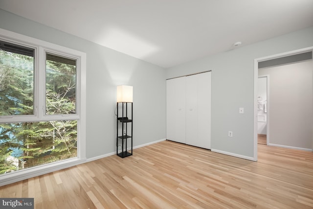 unfurnished bedroom featuring baseboards, light wood-style floors, and a closet