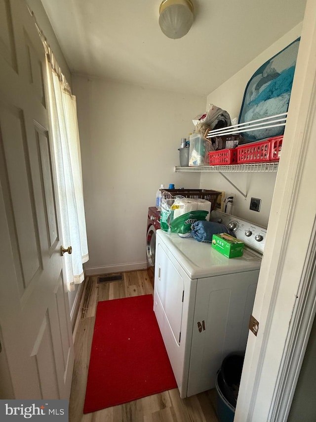 laundry room with laundry area, washer / dryer, and light wood-style flooring