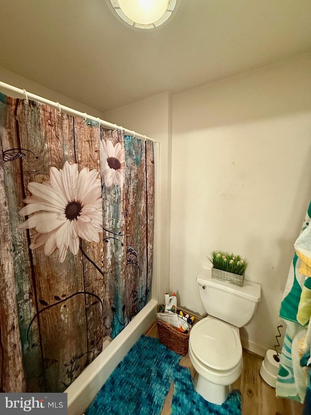 bathroom with toilet, a shower with curtain, and wood finished floors