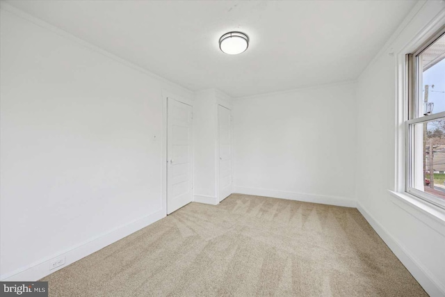 empty room with baseboards, a wealth of natural light, and light colored carpet