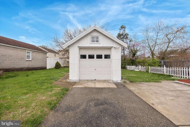 detached garage featuring aphalt driveway and fence