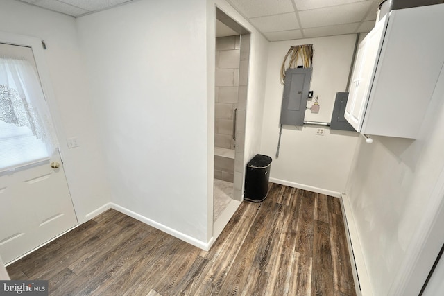 interior space featuring wood finished floors, electric panel, a drop ceiling, and baseboards