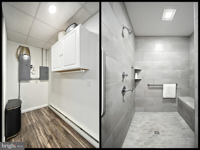 full bath featuring a tile shower, wood finished floors, and electric panel