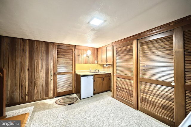 bar featuring wood walls, white dishwasher, and a sink