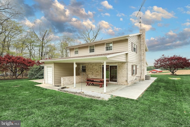 rear view of property with brick siding, a patio area, a lawn, and a chimney