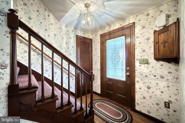 foyer with stairs, wood finished floors, and wallpapered walls