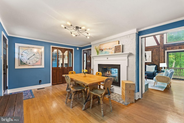 11713 Henderson Rd, Clifton, VA 20124 - dining room featuring a chandelier, light wood-type flooring, crown molding, a glass covered fireplace, and baseboards