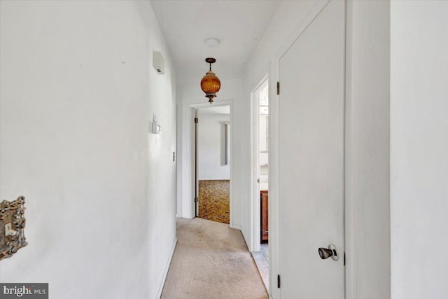 corridor featuring baseboards and light colored carpet