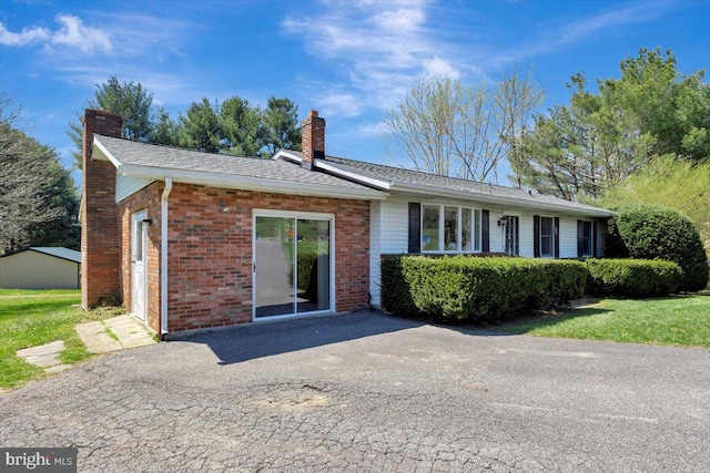view of front of property featuring a chimney and brick siding