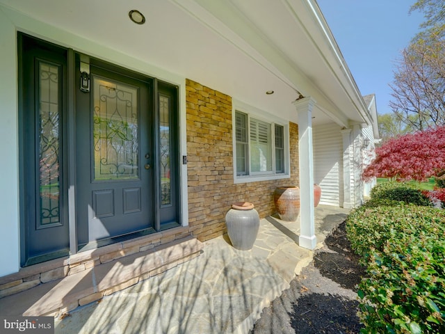 view of exterior entry featuring a porch and stone siding