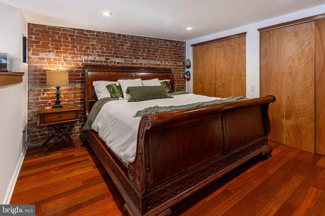 bedroom with two closets, wood finished floors, and recessed lighting