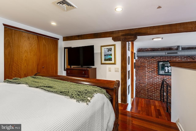 bedroom featuring hardwood / wood-style floors, brick wall, visible vents, and recessed lighting