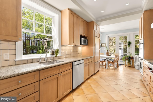 kitchen with decorative backsplash, light stone counters, a sink, light tile patterned floors, and stainless steel appliances