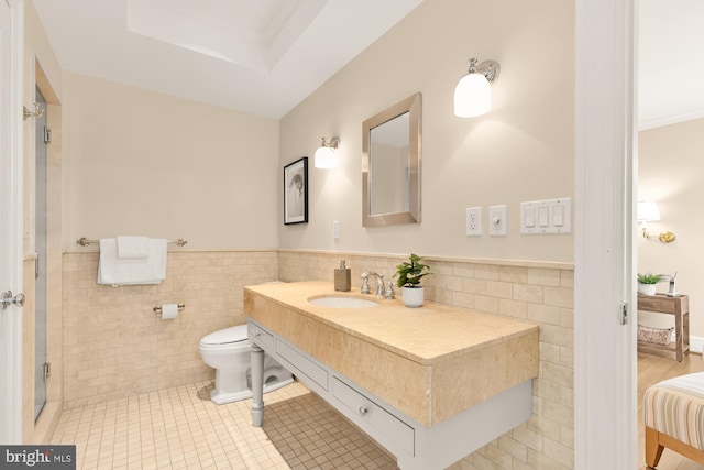 bathroom with vanity, wainscoting, toilet, tile walls, and tile patterned floors