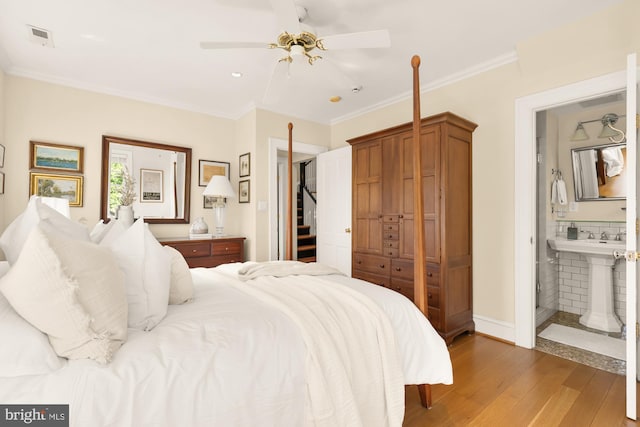bedroom with ceiling fan, ensuite bath, light wood-type flooring, visible vents, and ornamental molding