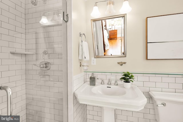 bathroom with a wainscoted wall, tile walls, toilet, and a shower stall
