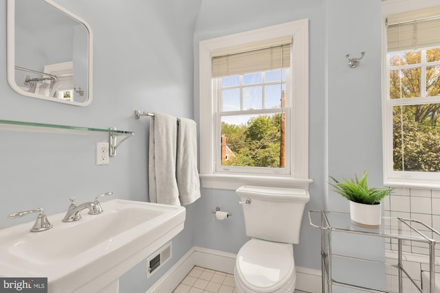 bathroom featuring toilet, baseboards, visible vents, and a wealth of natural light