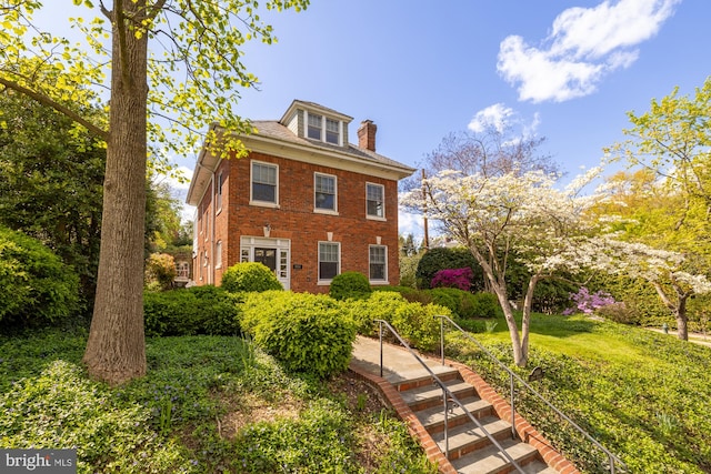 view of front of property with a chimney and brick siding