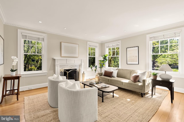 living area featuring crown molding, a fireplace, baseboards, recessed lighting, and light wood-style flooring