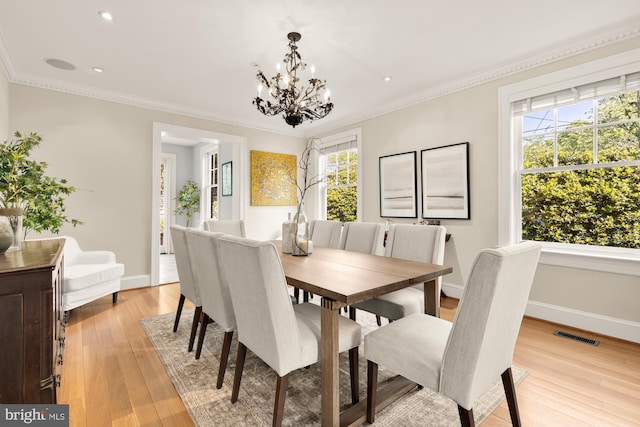 dining space with crown molding, baseboards, light wood finished floors, and a chandelier