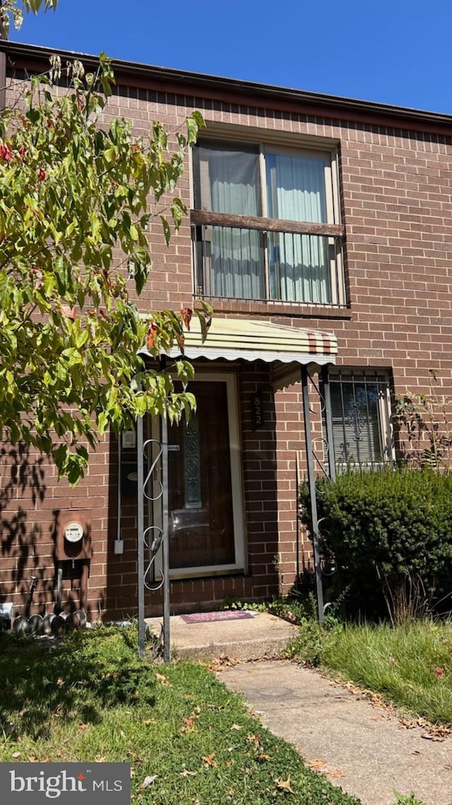 view of front of house featuring brick siding and a balcony