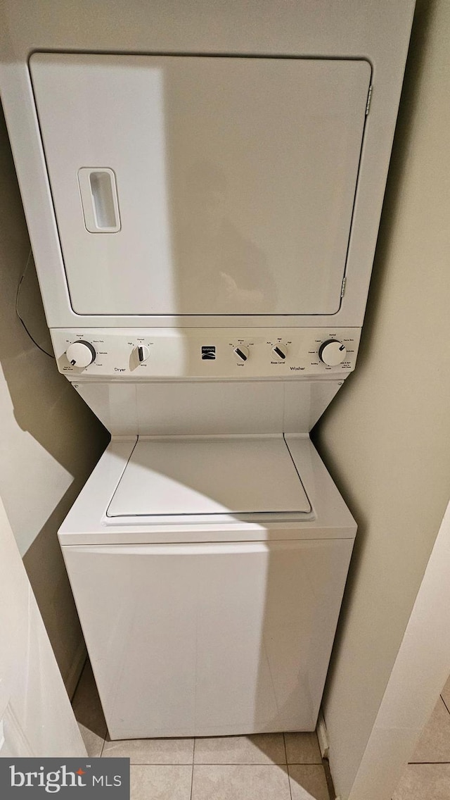 washroom featuring stacked washer / drying machine, laundry area, and light tile patterned floors
