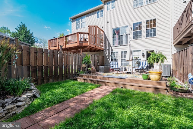 rear view of house featuring a lawn, a wooden deck, a fenced backyard, and central AC unit
