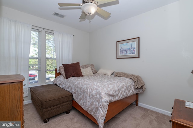 bedroom with visible vents, baseboards, ceiling fan, and light carpet