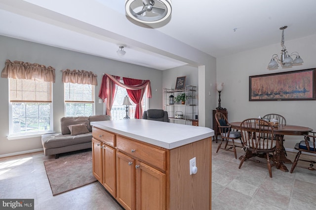 kitchen with an inviting chandelier, pendant lighting, open floor plan, a center island, and light countertops