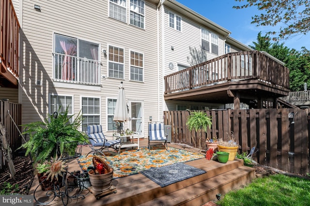 rear view of property featuring a wooden deck and fence