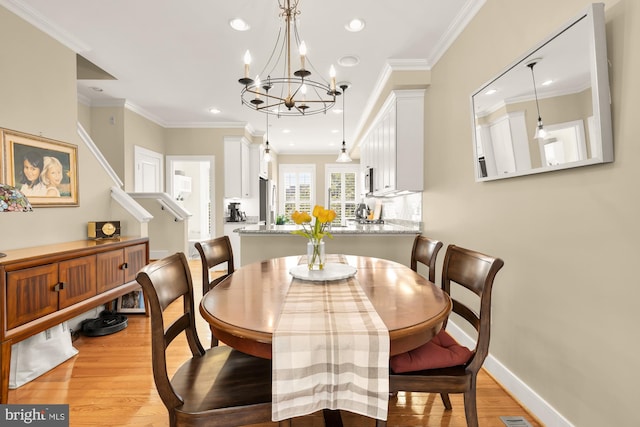 dining space featuring crown molding, a notable chandelier, light wood-type flooring, and recessed lighting