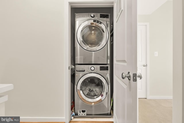 washroom with laundry area, stacked washer and dryer, baseboards, and carpet floors