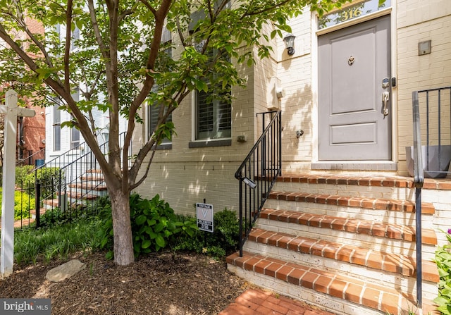 entrance to property featuring fence and brick siding