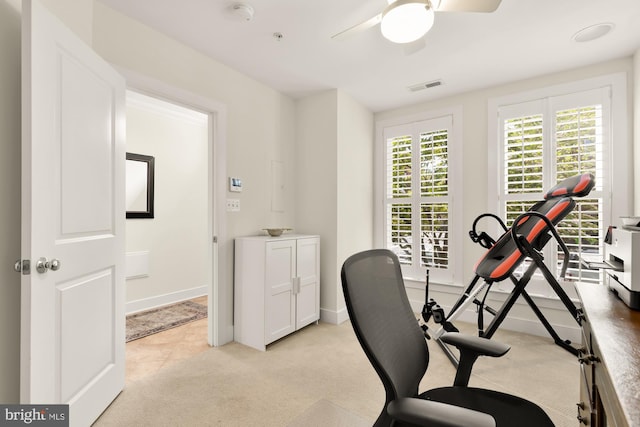 exercise room featuring light colored carpet, baseboards, ceiling fan, and visible vents