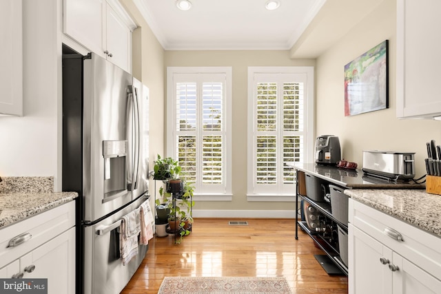 kitchen featuring light wood-style flooring, stainless steel fridge with ice dispenser, crown molding, white cabinets, and visible vents
