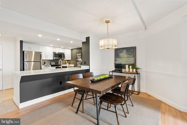 dining room with baseboards, light wood-style floors, and crown molding