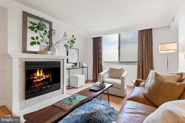 living area with ornamental molding, light wood-type flooring, a fireplace, visible vents, and a textured ceiling
