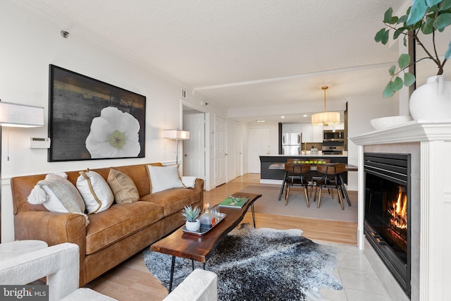 living room featuring visible vents, a textured ceiling, a warm lit fireplace, and crown molding