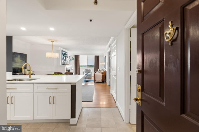 kitchen featuring white cabinetry, a sink, light countertops, open floor plan, and a peninsula