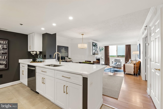 kitchen with white cabinets, a sink, light countertops, dishwashing machine, and a peninsula