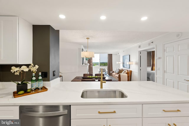 kitchen with light stone countertops, a sink, white cabinetry, dishwasher, and open floor plan