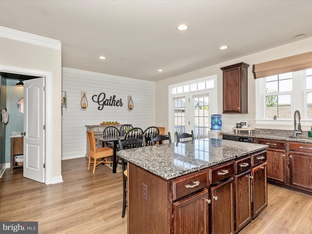 kitchen featuring a wealth of natural light, a kitchen breakfast bar, light stone counters, and a sink