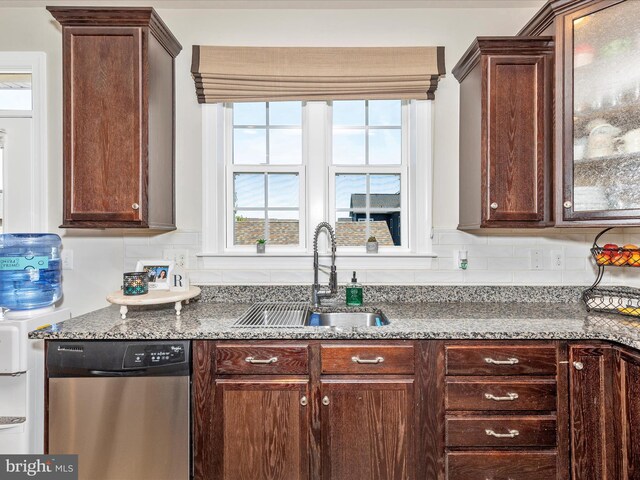 kitchen featuring stainless steel dishwasher, light stone counters, a sink, decorative backsplash, and glass insert cabinets