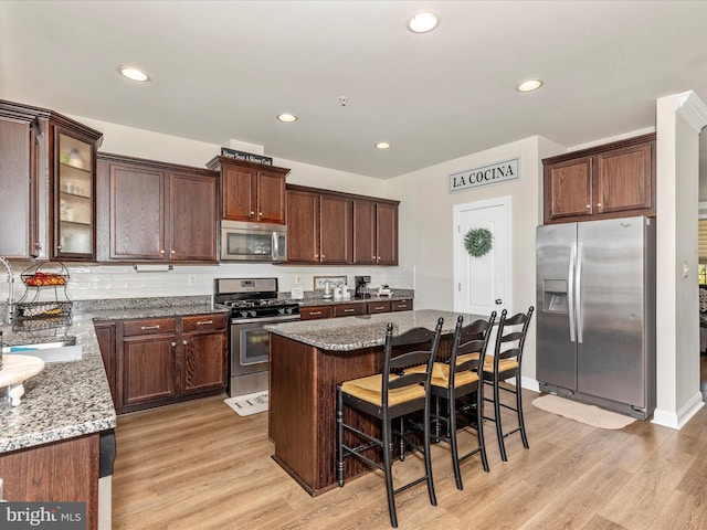 kitchen with appliances with stainless steel finishes, light stone counters, and light wood-type flooring
